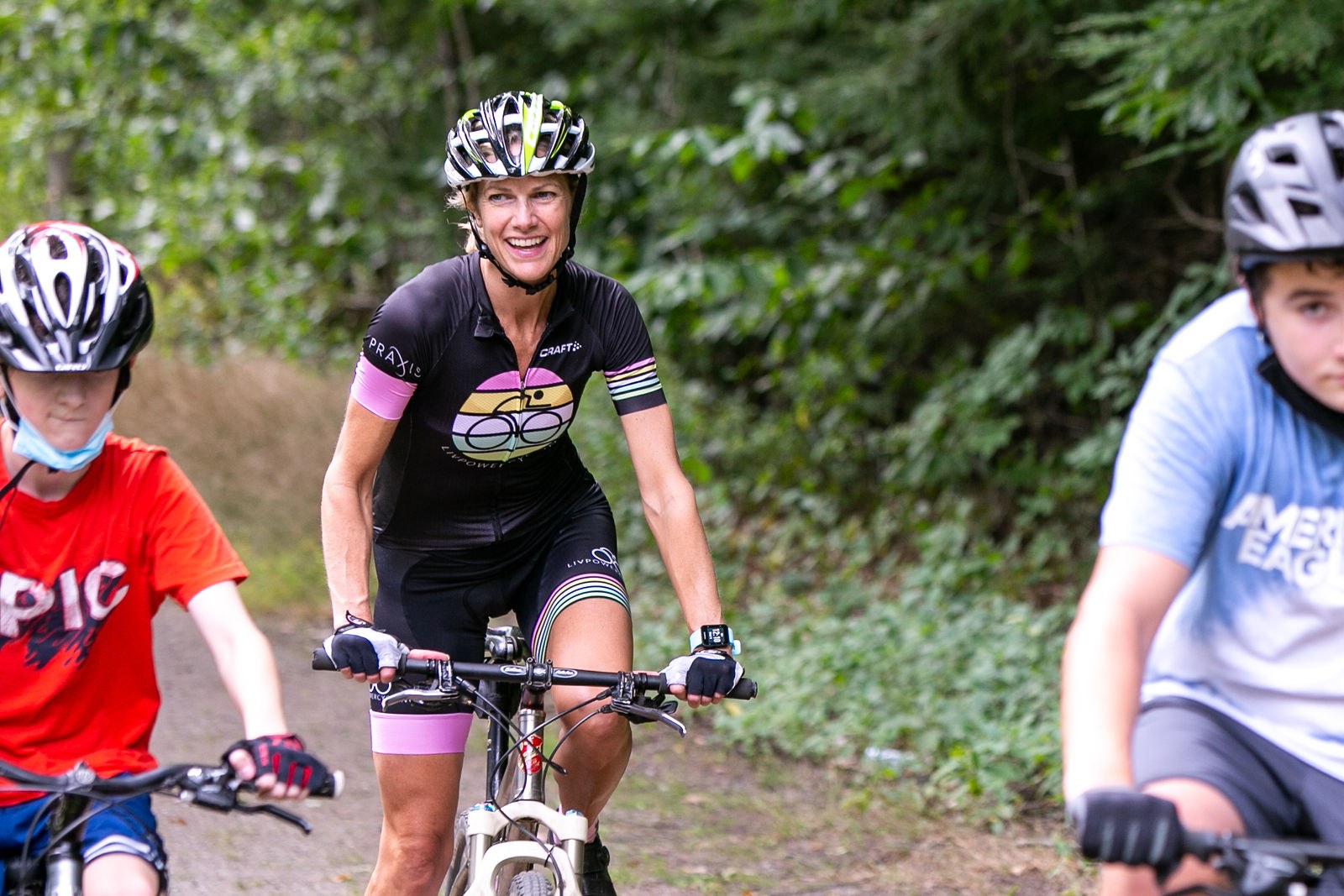 Val smiling as she leads young mountain bikers down a trail